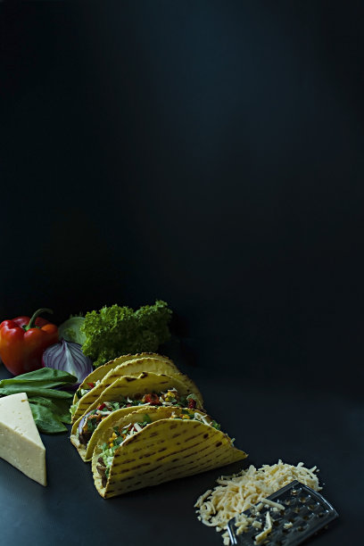 墨西哥玉米饼，猪肉，奶酪，玉米，洋葱和香草放在木板上的照片。加番茄酱和辣椒。黑色背景。侧视图。图片下载