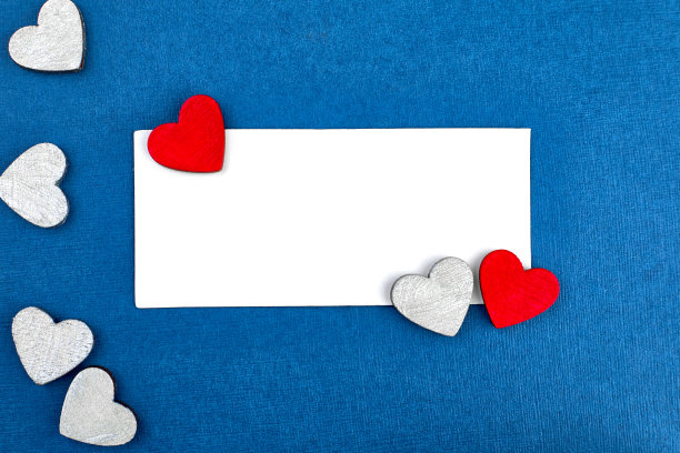 情人节设计:白色卡片，蓝色背景的红色和银色木制心形图案，祝贺你，爱的宣言。图片下载