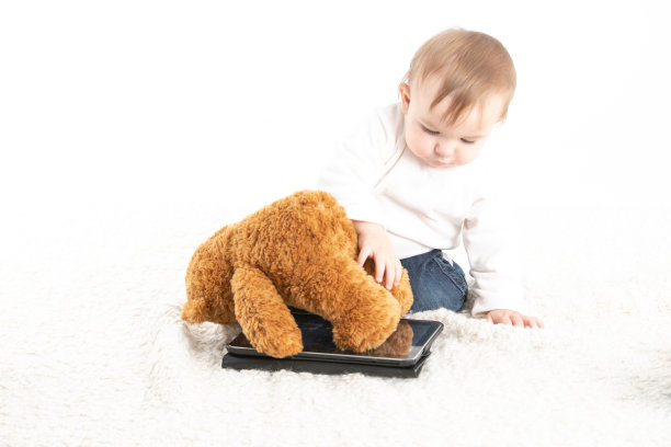 宝宝玩着平板电脑和泰迪熊图片下载