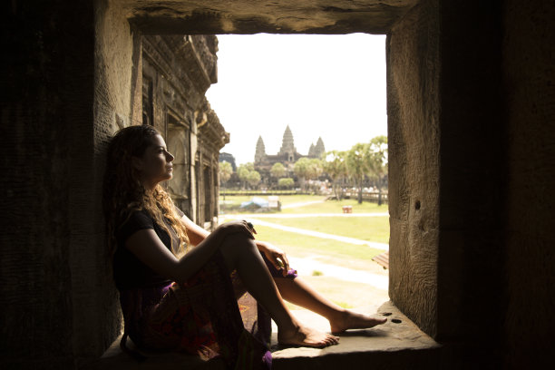 年轻女子，穿着衣服，旁边的窗口与吴哥窟的背景图片下载