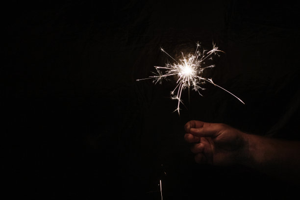 手与火花在黑暗的背景。用烟花庆祝新年。手持火花在黑暗的背景。圣诞的乐趣。新年的概念图片下载