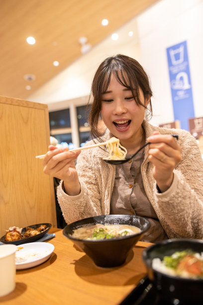 年轻的母亲和家人在美食广场吃拉面图片下载