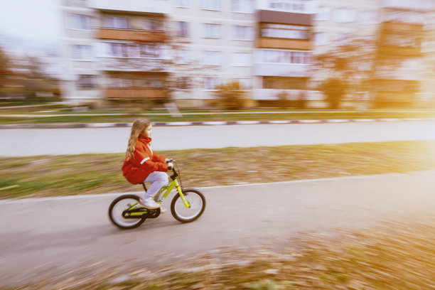 年轻的金发女孩穿着红夹克骑着自行车图片下载