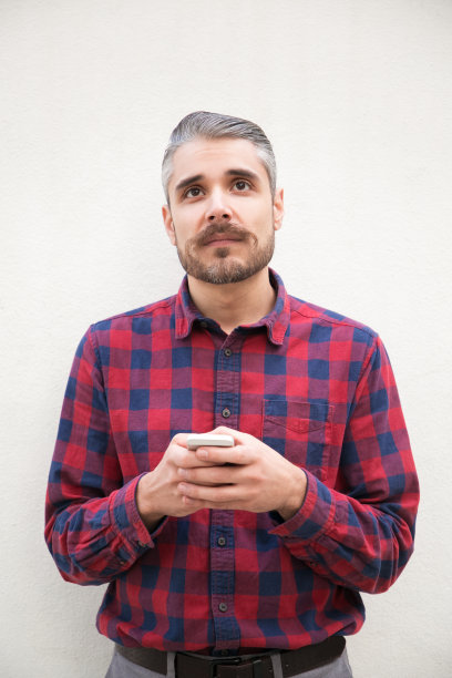 沉思的男人拿着智能手机，抬头看图片下载