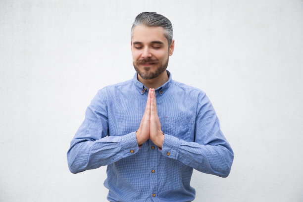 安静积极的男人闭着眼睛做合十礼的手势图片下载