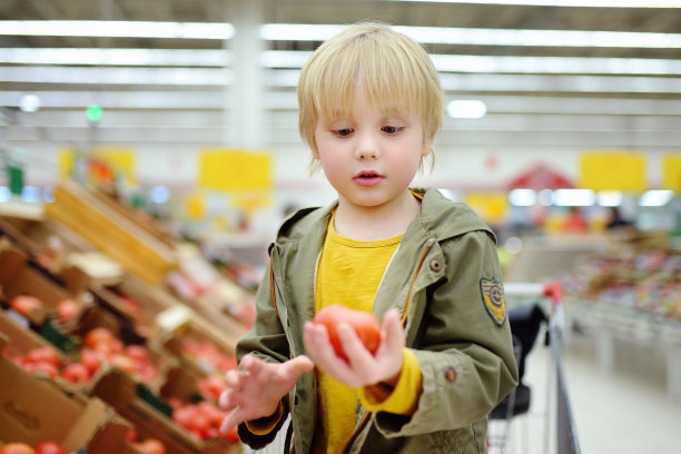 可爱的小男孩在食品店或超市挑选新鲜的有机番茄。图片下载