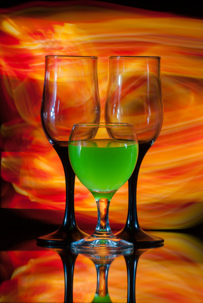 黄色背景上的三只眼镜。美丽的静物与绿色果汁图片下载