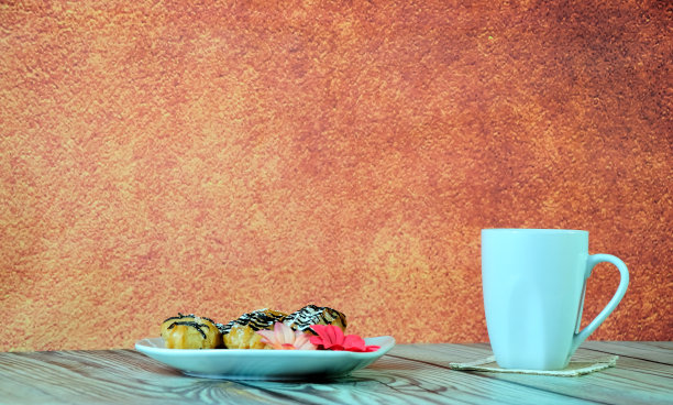 一个白色高脚杯，上面放着茶，餐巾上放着一个盘子，上面有泡芙和一个花蕾。图片下载