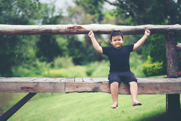 快乐的小男孩坐在木桥上图片下载