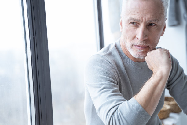 窗边沉思的男人看向别处的库存照片图片下载