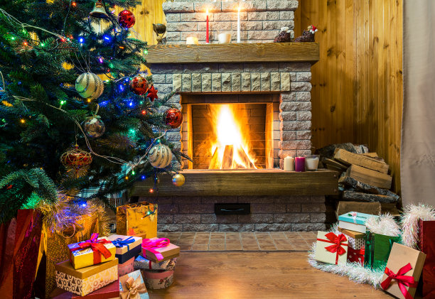 舒适的壁炉燃烧。圣诞树上装饰着玩具和圣诞彩灯，礼品盒和蜡烛等。图片下载