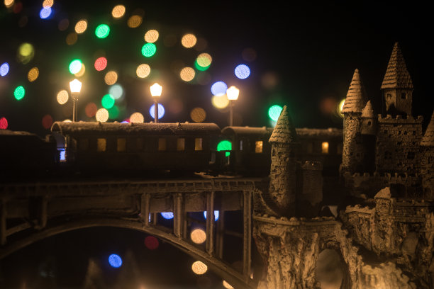 冬季雪景的缩影，桥上有火车，中世纪城堡和灯笼。假日属性。夜景。新年和圣诞节的概念。有选择性的重点图片下载