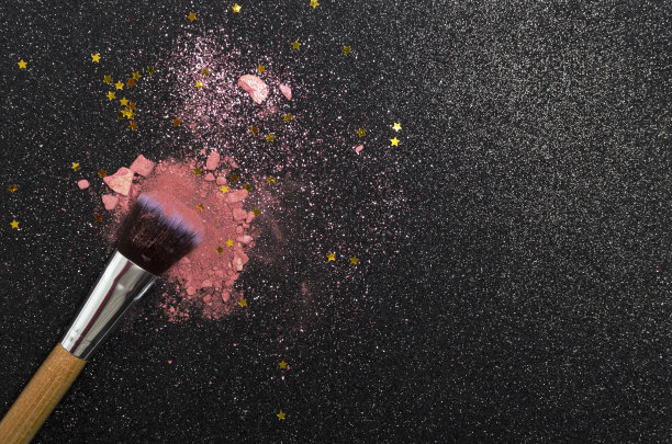 俯视图的粉色腮红，装饰亮片和星星派对化妆，刷与木制把手。设计空间图片下载
