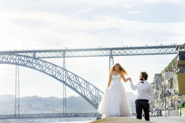 一对恩爱的新婚夫妇一头金发卷毛的男人走在一个大城市的路堤边上图片下载