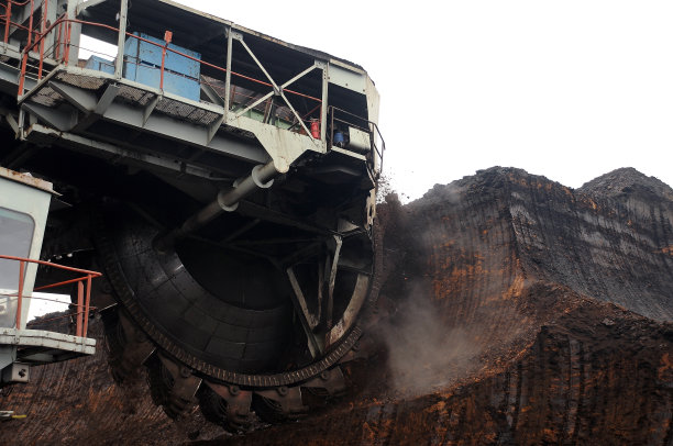 一个巨大的斗轮挖掘机在露天煤矿上挖煤。图片下载