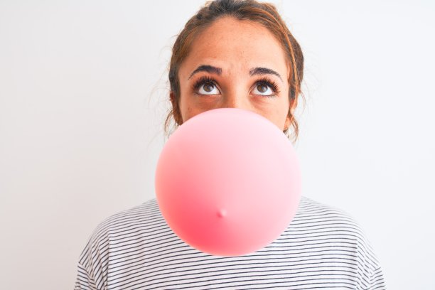 年轻的书迷现代女性一边嚼口香糖一边吹泡泡图片下载