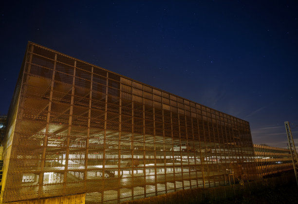 一个现代化的，部分照明的停车场建筑，在一个工业区，星空下图片下载