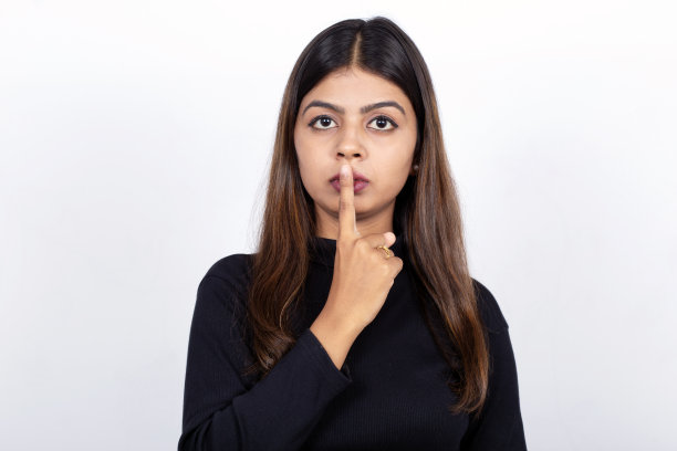 自信的年轻印度女商人与手指上的嘴唇在白色的背景图片下载