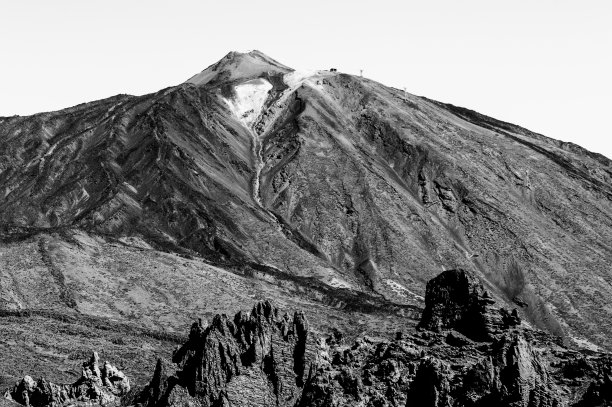 在一个阳光明媚的晴天，在El Teide国家公园的最高的山峰后面的熔岩岩石的黑白照片。图片下载