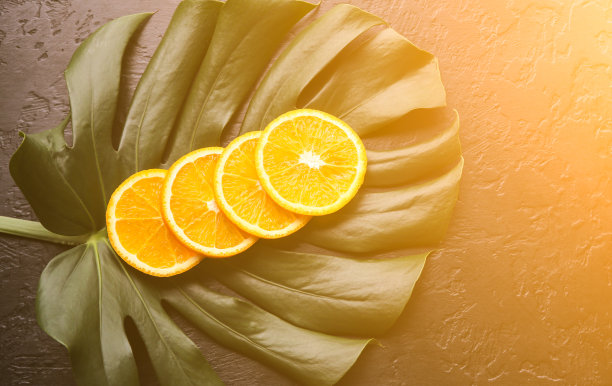 绿色热带叶子上的橙子。怪物室内植物在黑色的背景。生态友好的照片。图片下载