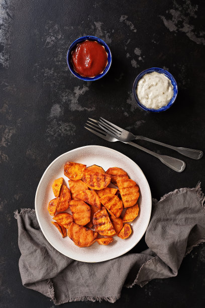 烤红薯，蕃茄和大蒜酱在黑色的石头背景。俯视图，平放。图片下载