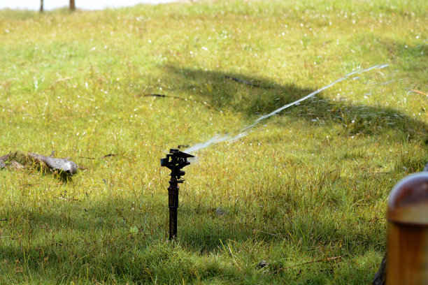 草坪洒水车在夏天喷水。自动浇水设备和草坪养护图片下载
