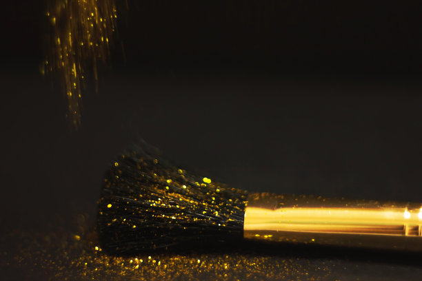 化妆刷和设计上的金色闪光纹理。在白色背景上。选择性聚焦-图像图片下载