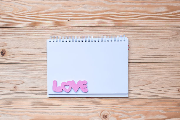 爱的文字与笔记本木桌子的背景。浪漫情人节的概念图片下载