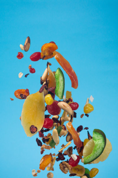 干果、蜜饯和坚果在蓝色背景上飞舞。健康和营养食物的库存照片。图片下载