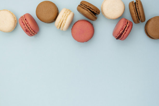 马卡龙蛋糕。抽象的食物照片背景与美味的杏仁饼干在蓝色的背景。平铺社交媒体墙纸。副本的空间。图片下载