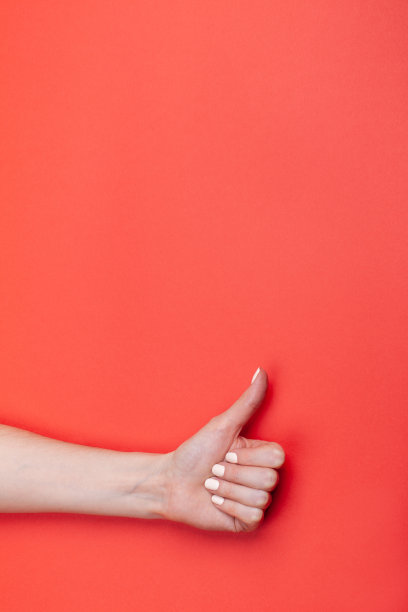 特写女性的手显示拇指向上的红色背景图片下载