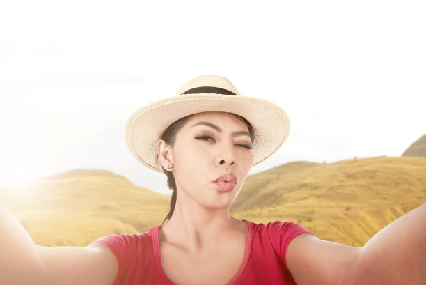 戴着帽子的亚洲女孩用照相手机自拍一张有趣的脸图片下载