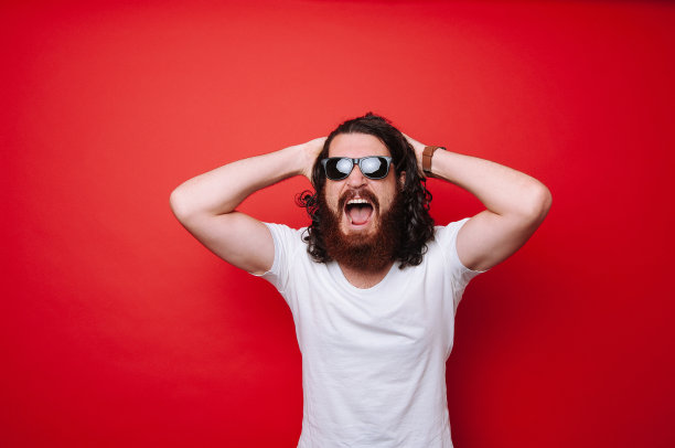 年轻的大胡子男子在红色背景下尖叫图片下载