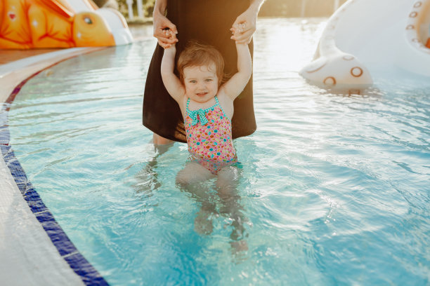 一个女人在游泳池里牵着小孩图片下载