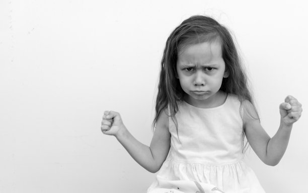 愤怒和好斗的年轻女孩紧咬着牙齿和拳头看着镜头。孤立在白色背景上。黑白照片。儿童情绪和攻击性的概念图片下载