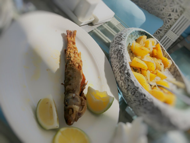 盘中炸鱼配青柠片，背景是洋葱炒土豆图片下载