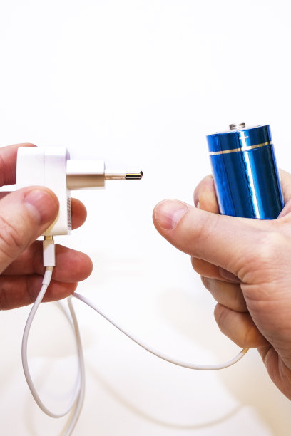 一个白底男子手中的电池和充电器。孤立。能量储存。图片下载