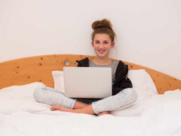 女孩坐在床上用手提电脑学习图片下载