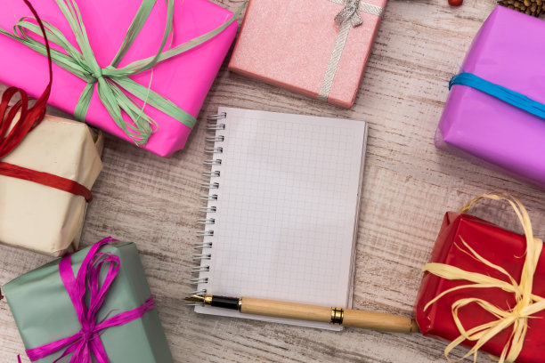 新年计划。空记事本和彩色礼品盒在轻桌上图片下载