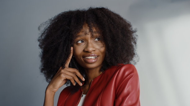 迷人的黑人女孩与郁郁葱葱的卷发摆姿势为时尚杂志拍摄照片。女孩顽皮地微笑，表演和玩面部表情。在专业工作室拍摄。肖像拍摄图片下载