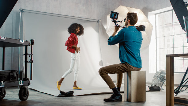 美丽的黑人模特摆姿势的视频剪辑，摄影师拍摄她。她玩面部表情。时尚的时尚杂志。用专业设备在工作室拍摄照片图片下载