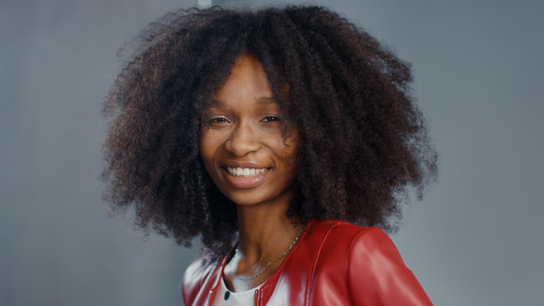 迷人的黑人女孩与郁郁葱葱的卷发摆姿势为时尚杂志拍摄照片。美丽的女孩微笑在专业摄影棚拍摄的时尚杂志。肖像拍摄图片下载