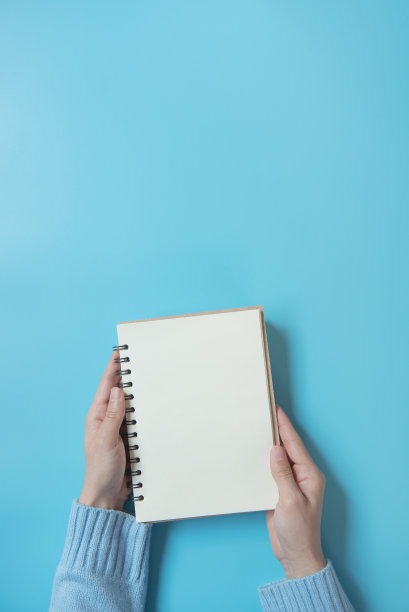 手握空白翻开书模拟与白色页上的蓝色背景，拷贝空间。图片下载