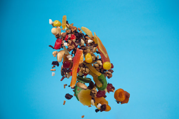 干果、蜜饯和坚果在蓝色背景上飞舞。健康和营养食物的库存照片。图片下载