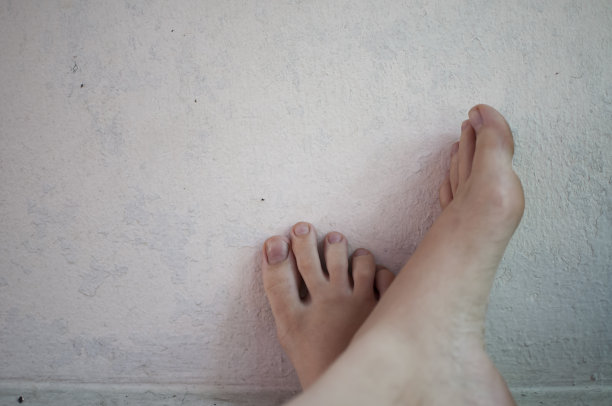 女人的脚搁在白色的墙上。图片下载