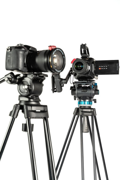 影院摄像机和无反光镜单反相机三脚架上白色工作室背景垂直图片下载