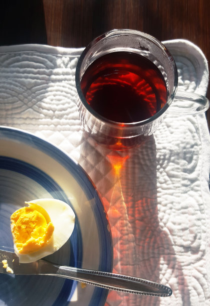 在早晨的阳光下，一杯茶和吃了一半的煮鸡蛋的顶视图。图片下载