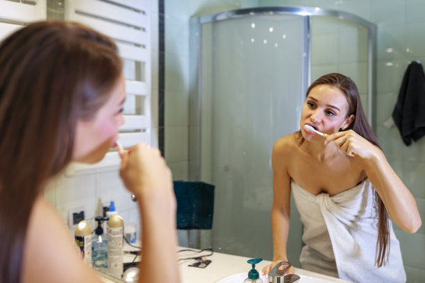 一个女人正在镜子前刷牙图片下载