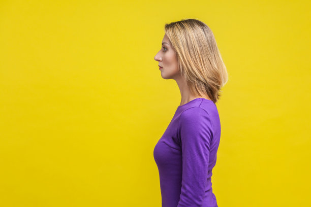 侧面的年轻自信的女商人看着严肃聪明的表情。孤立在黄色背景上图片下载