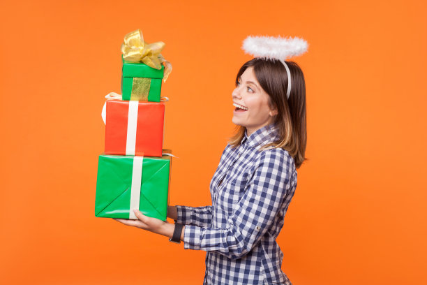 侧视图肖像可爱的天使深色头发的女人在格子衬衫与晕在头上。橙色背景隔离图片下载